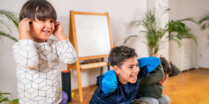 Three brothers smiling and doing exercise in their at-home learning space.